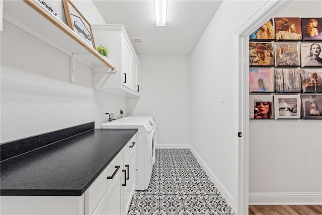 clothes washing area featuring visible vents, washing machine and dryer, cabinet space, and baseboards