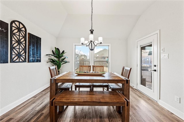 dining room with lofted ceiling, a notable chandelier, wood finished floors, and baseboards