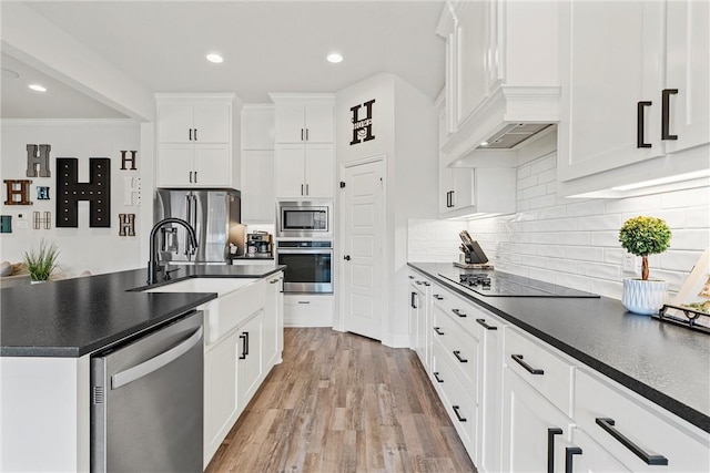 kitchen with dark countertops, premium range hood, white cabinets, and stainless steel appliances