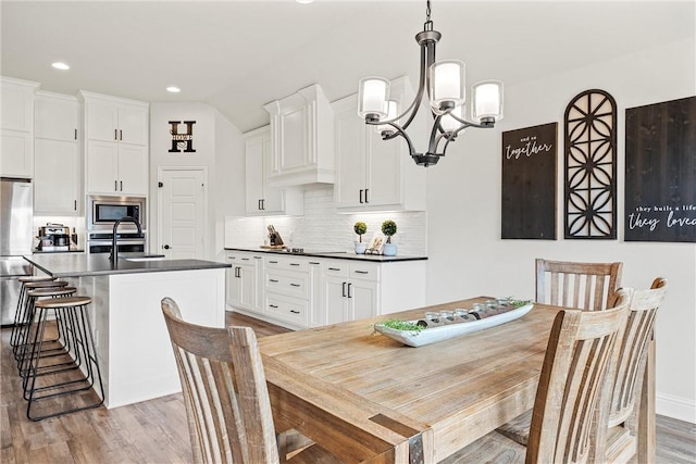 dining area with a chandelier, light wood finished floors, lofted ceiling, and recessed lighting