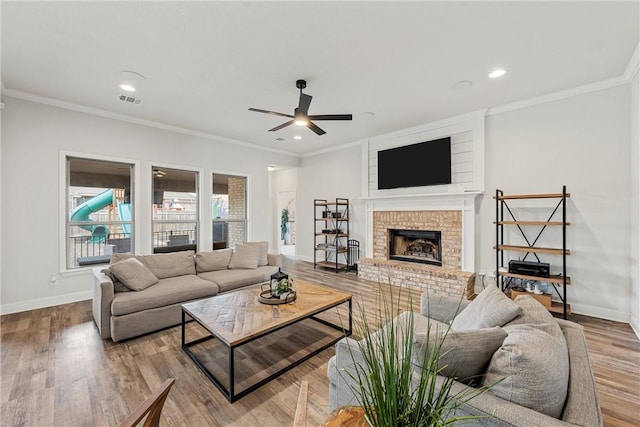 living area with a fireplace, wood finished floors, visible vents, and baseboards