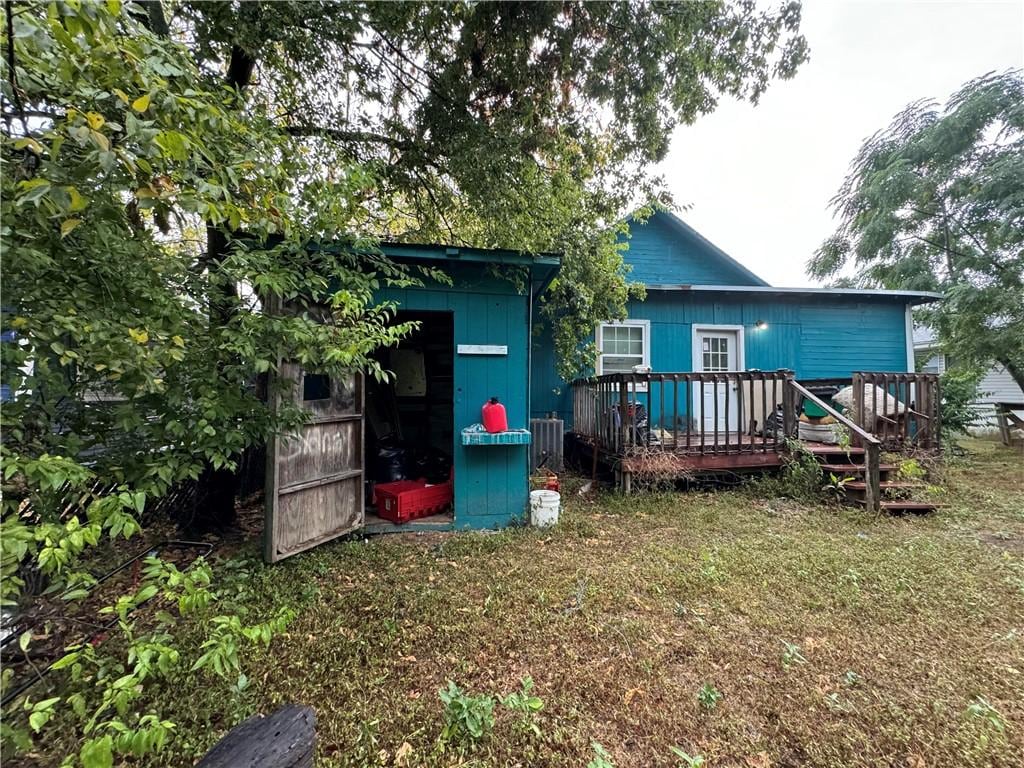 rear view of house featuring a wooden deck and a storage shed