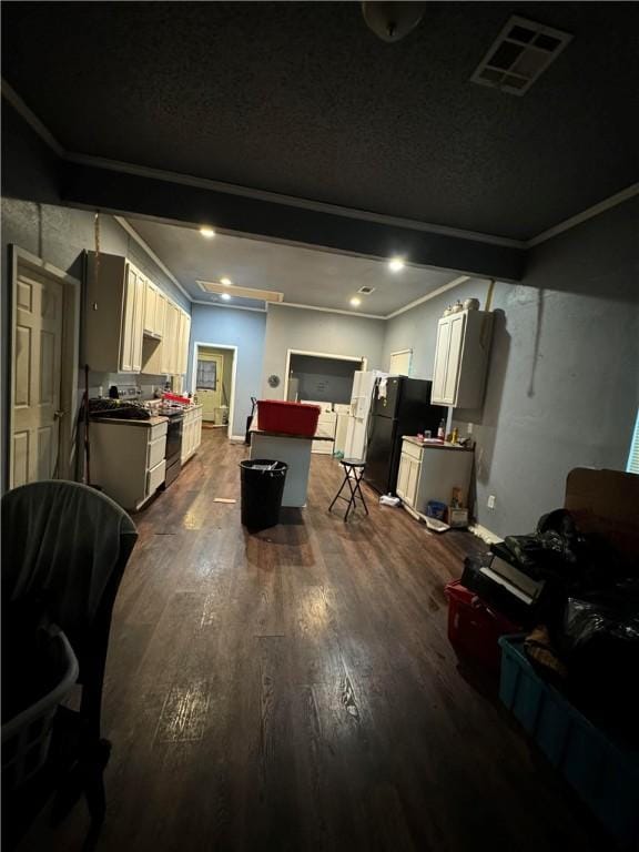 interior space with black fridge, ornamental molding, stainless steel range, white cabinets, and dark hardwood / wood-style floors