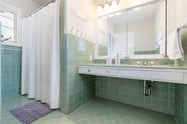 full bath with tile patterned flooring, a sink, and tile walls