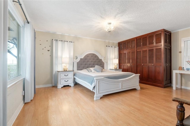 bedroom with ornamental molding, baseboards, a textured ceiling, and light wood finished floors