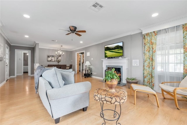 living area featuring ornamental molding, light wood-type flooring, visible vents, and a fireplace