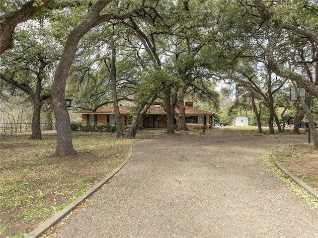 view of front of property featuring driveway, an outdoor structure, and a shed