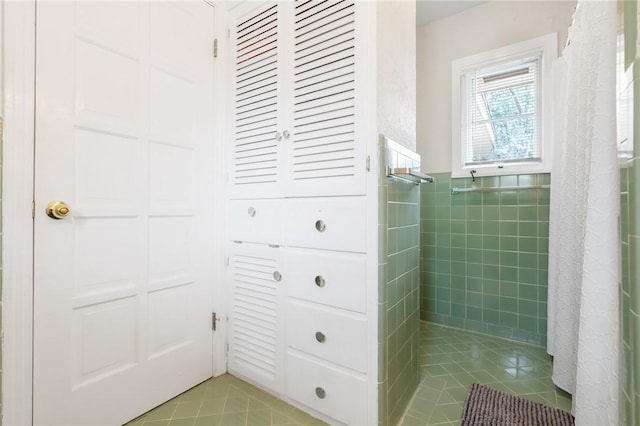 bathroom featuring a tile shower, tile walls, and tile patterned floors