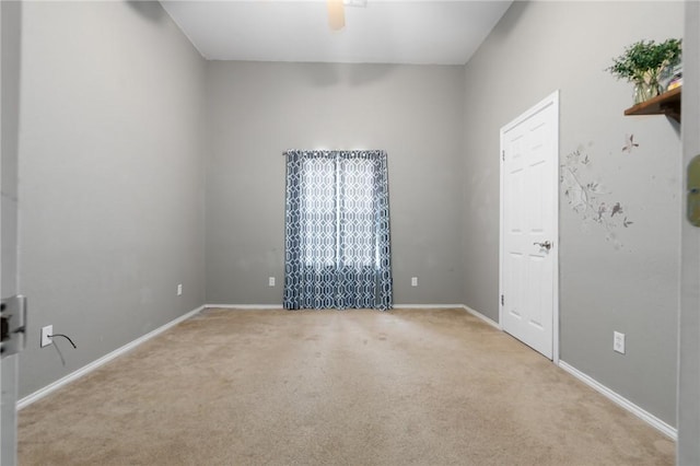 carpeted spare room featuring ceiling fan and baseboards