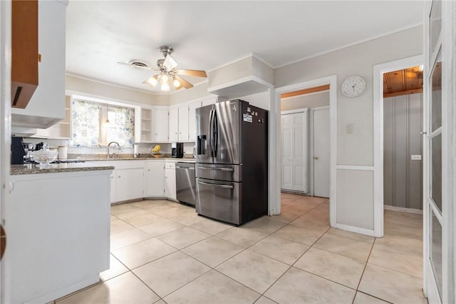 kitchen featuring light tile patterned floors, stainless steel appliances, a sink, white cabinetry, and a ceiling fan