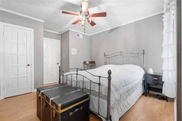 bedroom featuring crown molding, a textured ceiling, visible vents, and wood finished floors