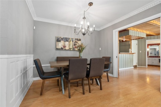 dining space featuring light wood finished floors, baseboards, ornamental molding, and a chandelier