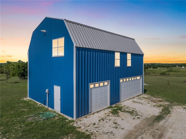 garage at dusk featuring a yard