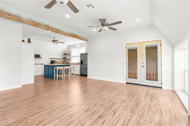 unfurnished living room featuring lofted ceiling, light hardwood / wood-style flooring, and french doors