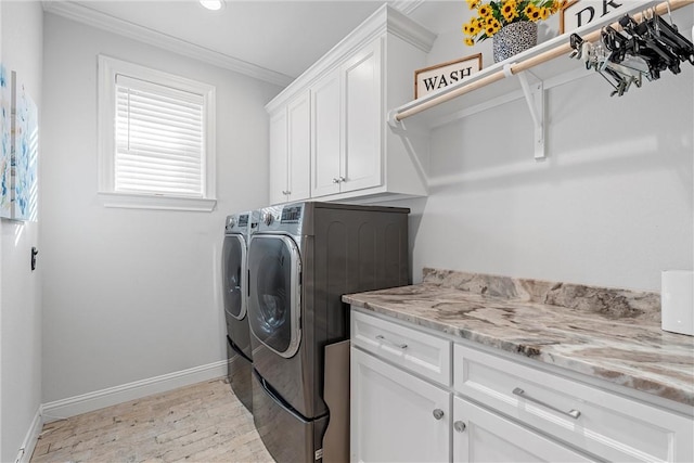 laundry room featuring baseboards, cabinet space, crown molding, and washer and clothes dryer