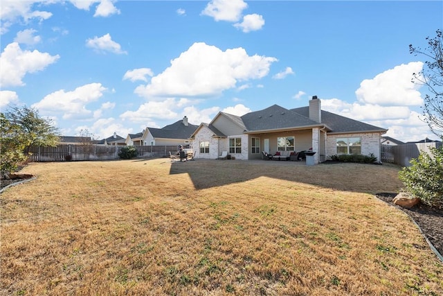 rear view of property featuring a fenced backyard, a patio area, a chimney, and a yard