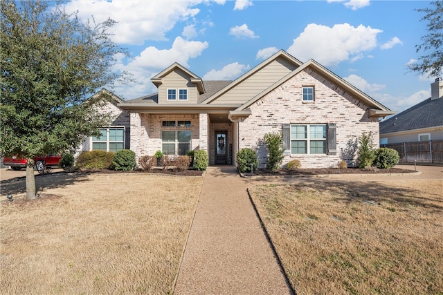 craftsman-style house with a front yard, fence, and brick siding