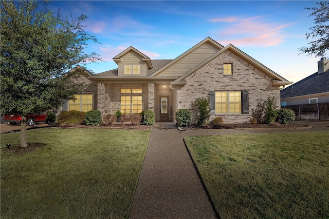 view of front of home featuring brick siding and a yard