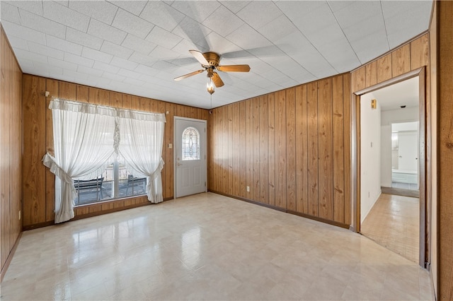 foyer featuring ceiling fan and wood walls