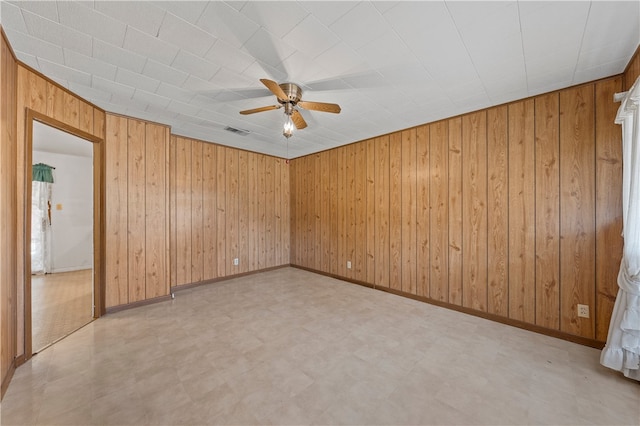 unfurnished room featuring wood walls and ceiling fan