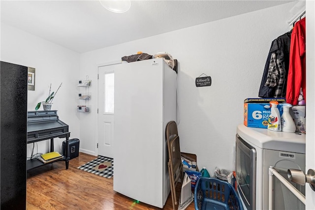 clothes washing area featuring laundry area, washer / clothes dryer, and wood finished floors