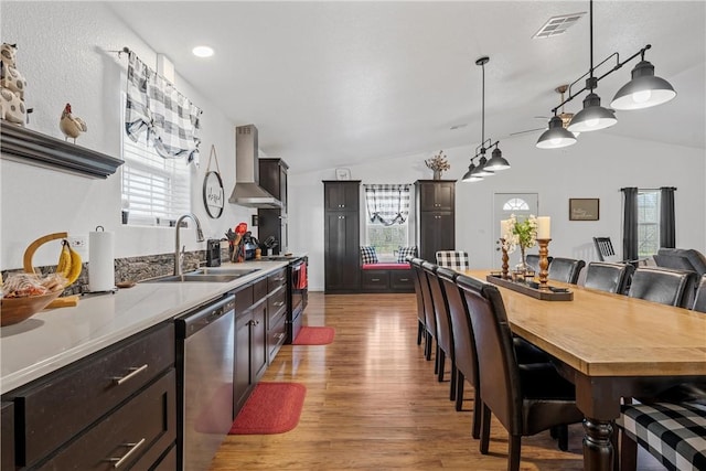 kitchen featuring light wood-type flooring, electric stove, a sink, wall chimney range hood, and dishwasher