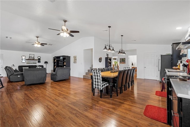 dining room with a ceiling fan, visible vents, dark wood-style flooring, stairs, and vaulted ceiling