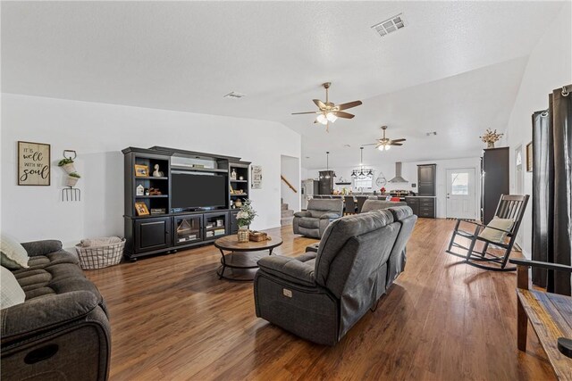 living room featuring wood finished floors, visible vents, lofted ceiling, ceiling fan, and stairs