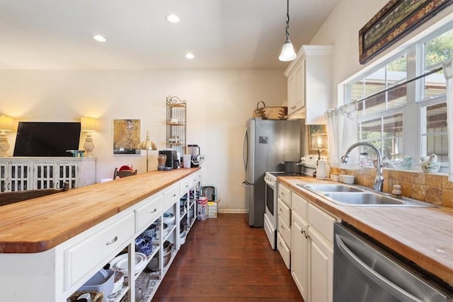 kitchen featuring wood counters, appliances with stainless steel finishes, dark hardwood / wood-style flooring, white cabinetry, and hanging light fixtures