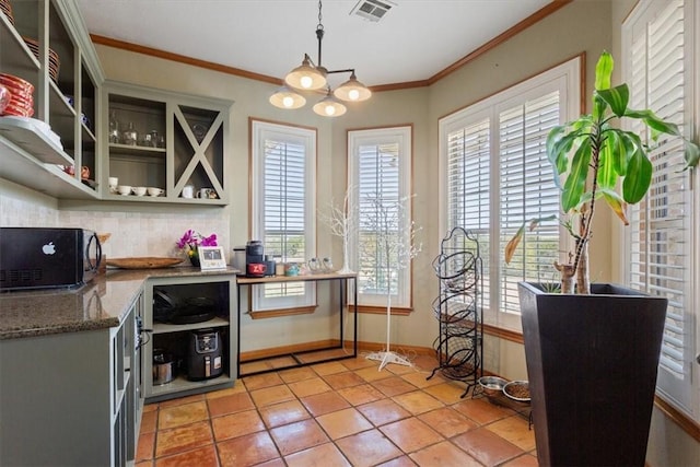 kitchen with decorative light fixtures, a wealth of natural light, and ornamental molding