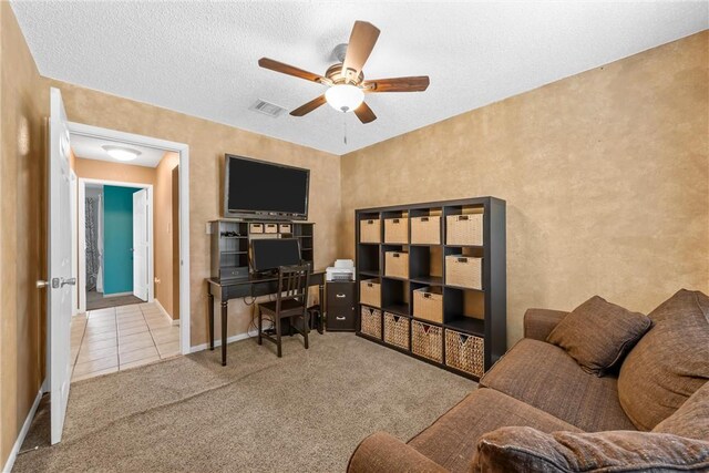 carpeted home office featuring visible vents, a ceiling fan, a textured ceiling, tile patterned flooring, and baseboards