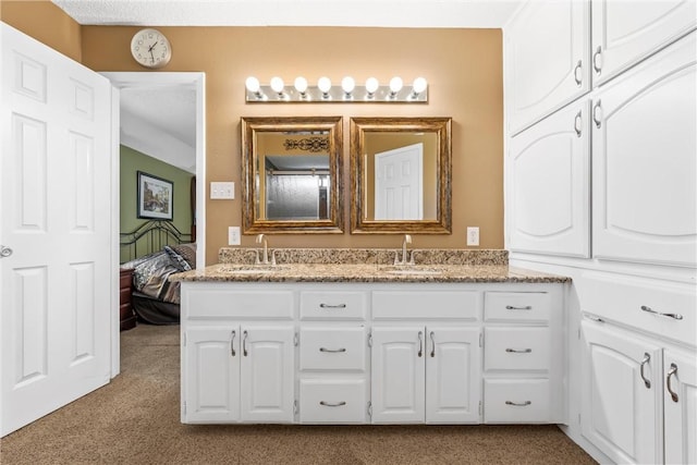 ensuite bathroom with double vanity, connected bathroom, and a sink