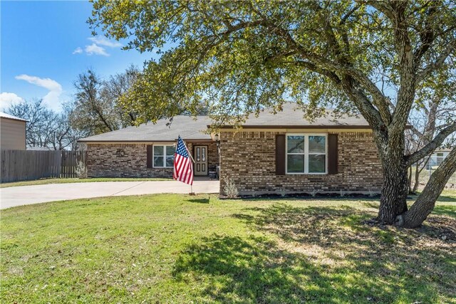 ranch-style home with driveway, brick siding, a front yard, and fence