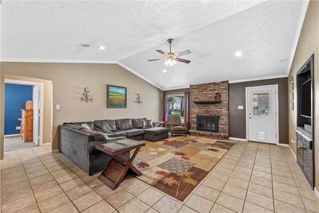 living room with a textured ceiling, light tile patterned flooring, a fireplace, ceiling fan, and vaulted ceiling