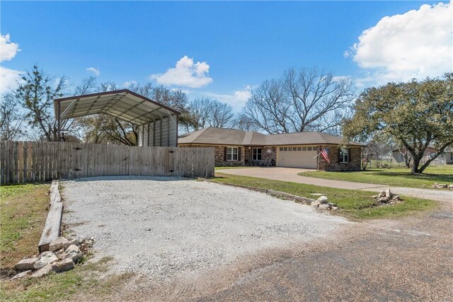 view of front of home featuring fence, gravel driveway, a detached carport, a front yard, and a garage