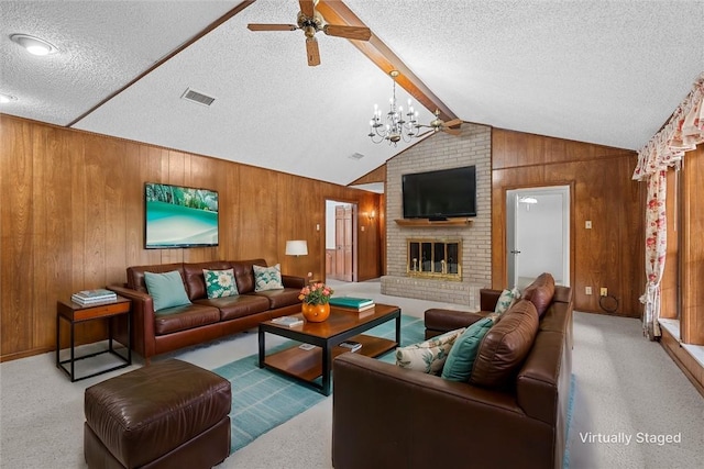 carpeted living room with a textured ceiling, wooden walls, and a fireplace