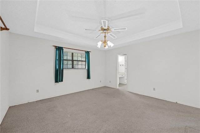 empty room with ceiling fan, light colored carpet, a textured ceiling, and a raised ceiling