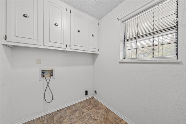 laundry area with washer hookup, a textured ceiling, and cabinets