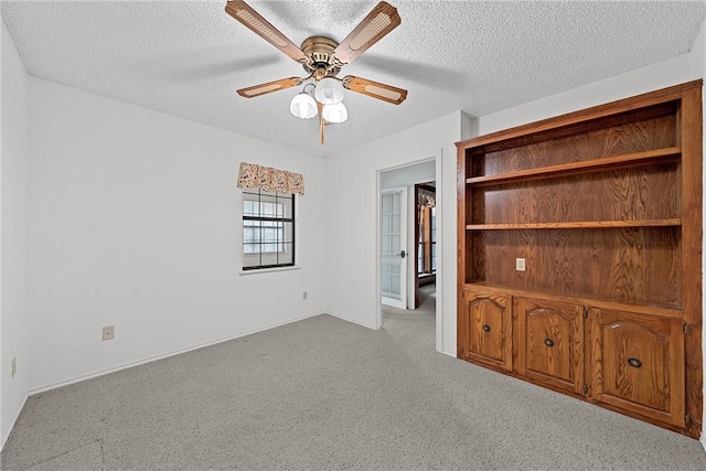 interior space with ceiling fan, light carpet, and a textured ceiling