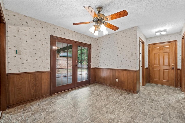 empty room featuring ceiling fan, french doors, and a textured ceiling