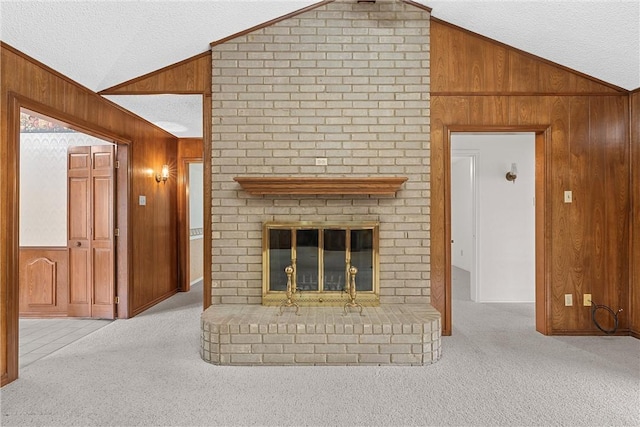 unfurnished living room with lofted ceiling, light colored carpet, a fireplace, wood walls, and a textured ceiling