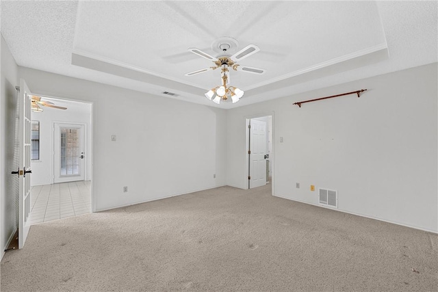 carpeted empty room featuring a raised ceiling, ceiling fan, crown molding, and a textured ceiling