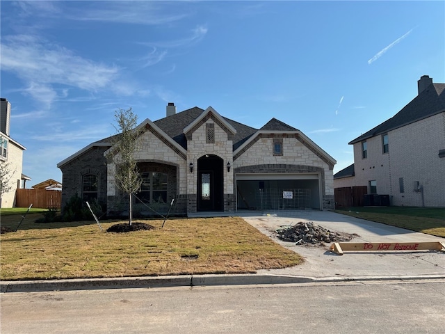 french provincial home featuring central AC, a front lawn, and a garage