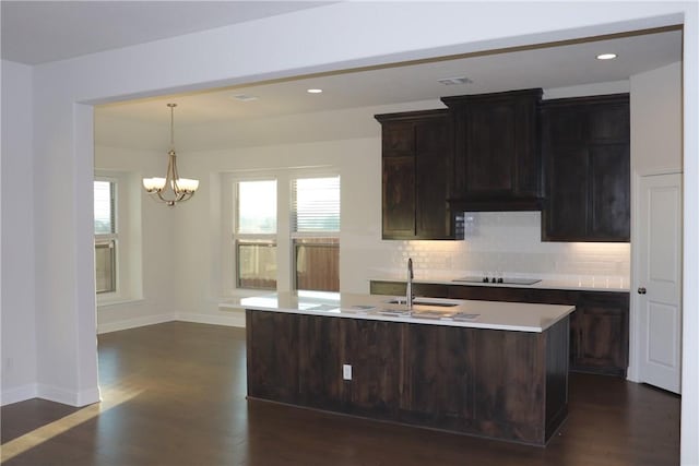 kitchen featuring dark brown cabinetry, an island with sink, decorative light fixtures, and sink