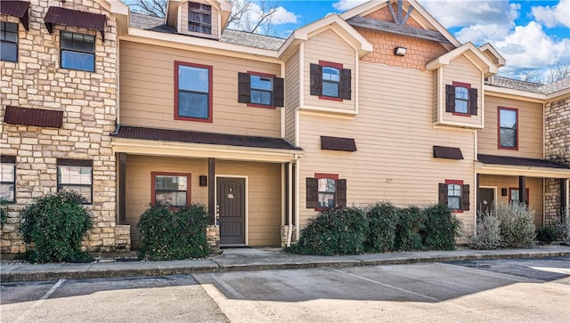 view of property with uncovered parking and stone siding