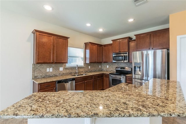 kitchen featuring sink, light stone countertops, stainless steel appliances, and tasteful backsplash