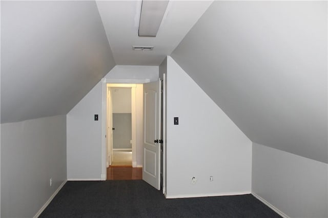 bonus room with dark carpet and lofted ceiling