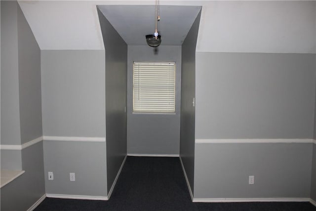 interior space featuring lofted ceiling and dark colored carpet