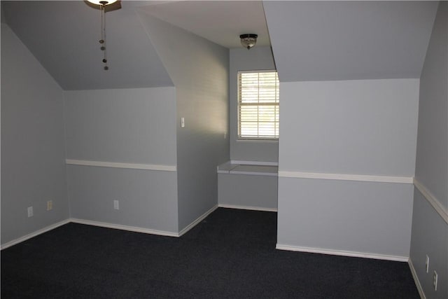 additional living space with dark colored carpet and lofted ceiling