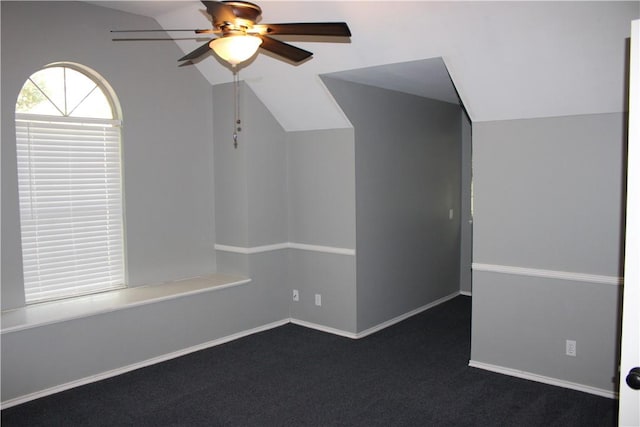 spare room featuring dark carpet, ceiling fan, and lofted ceiling